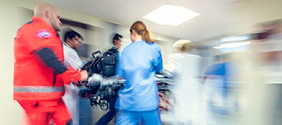 Paramedics and hospital clinicians rush a patient into an emergency room.