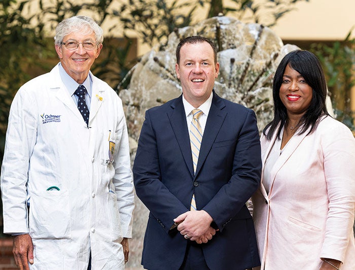 Three people posing for a photo, one dressed as a doctor, and the other two dressed formally.