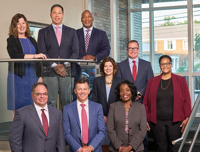 Representatives of the university hospital dressed professionally, standing on the staircase of a building and posing for a professional picture