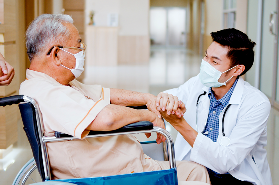 Access to Care. A clinician holds the hand of an elderly patient in a wheelchair.